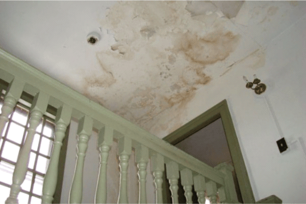 Water damage to ceiling inside home: discolouration, flaking paint and sheet particles